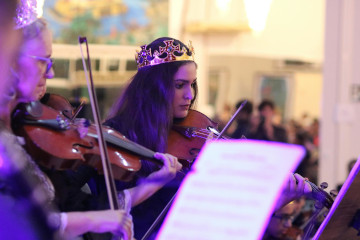 Photo of women playing violins in an orchestra